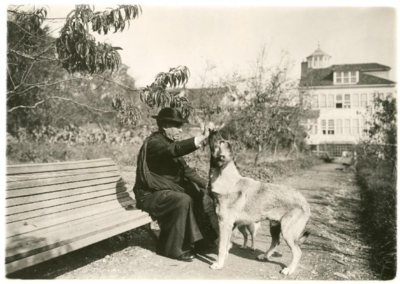 Retrato del sacerdote Cuevas jugando con dos perros